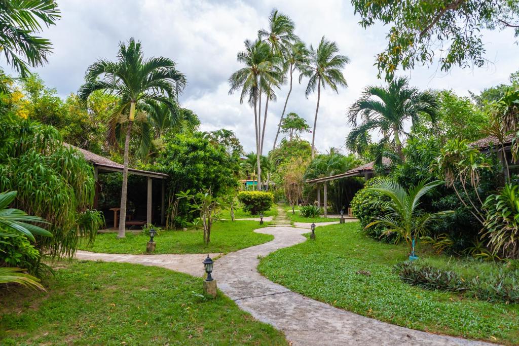 un chemin à travers un jardin planté de palmiers dans l'établissement Satva Samui Yoga and Wellness Resort, à Nathon Bay