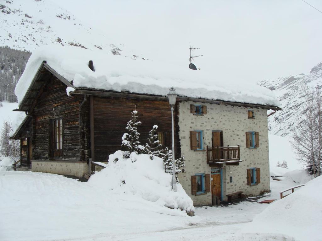 Cabaña de madera con nieve en el techo en Livigno Chalets, en Livigno