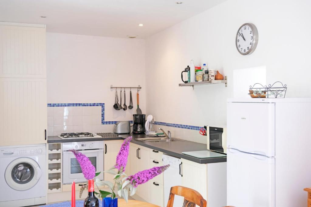 a kitchen with white appliances and a table with purple flowers at Lescoat-le petit paradis in Plestin-les-Grèves