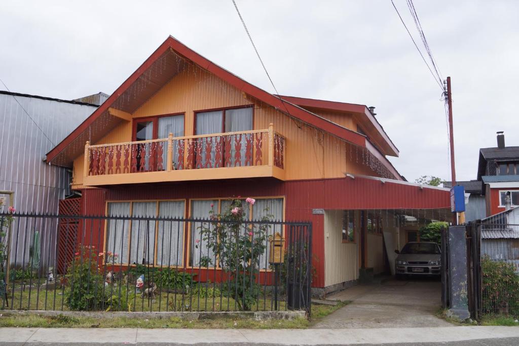 a red and orange house with a balcony at Casa Chilhué - Hostal Residencial in Castro