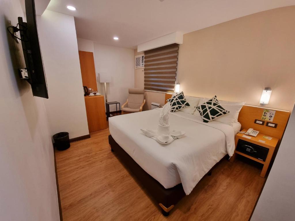 プエルト・プリンセサにあるALVEA HOTELの白い大型ベッド1台、テーブルが備わる客室です。