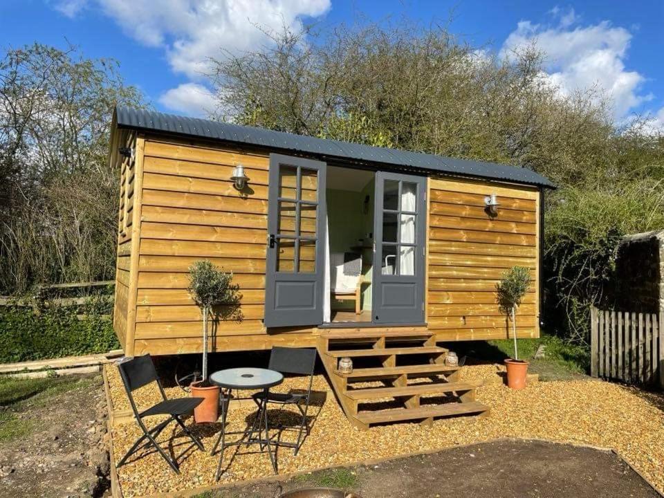 a small wooden cabin with a table and chairs at Hettie Luxury shepherds hut in Semley