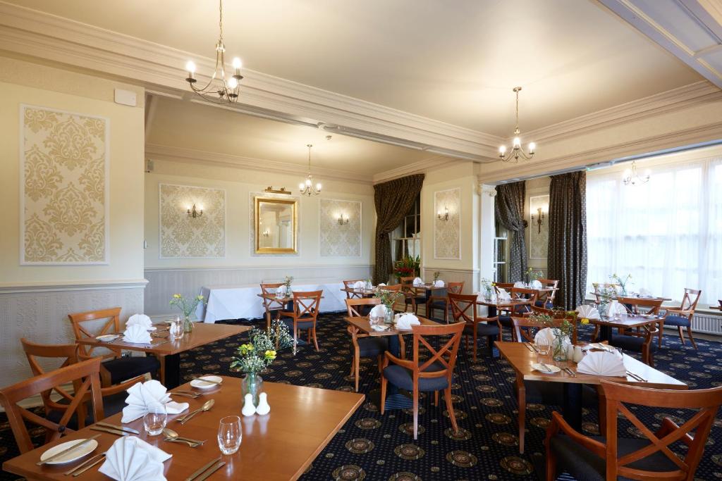 a dining room with wooden tables and chairs at Old Hunstanton Le Strange Arms Hotel in Hunstanton
