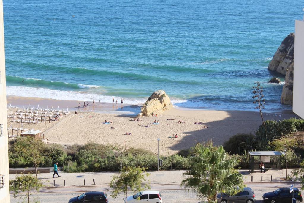 a beach with people on the sand and the ocean at Varandas Do Sol 2 in Portimão