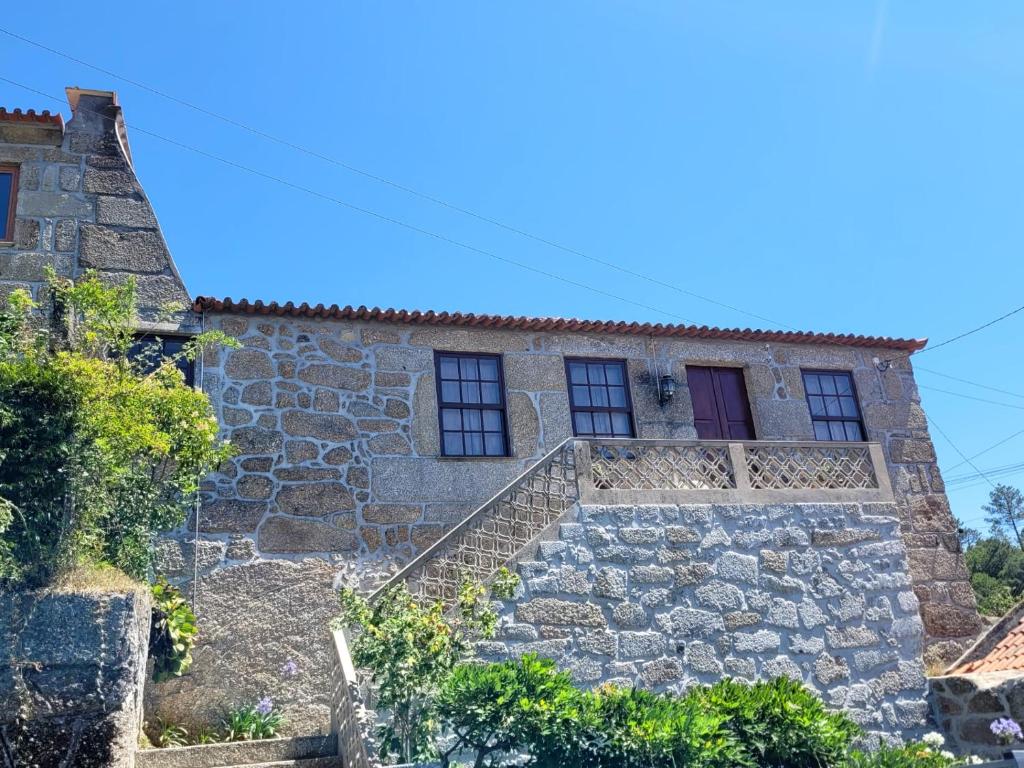 ein altes Steinhaus mit einer roten Tür in der Unterkunft Casa Dos Strecht's in Castelo de Paiva