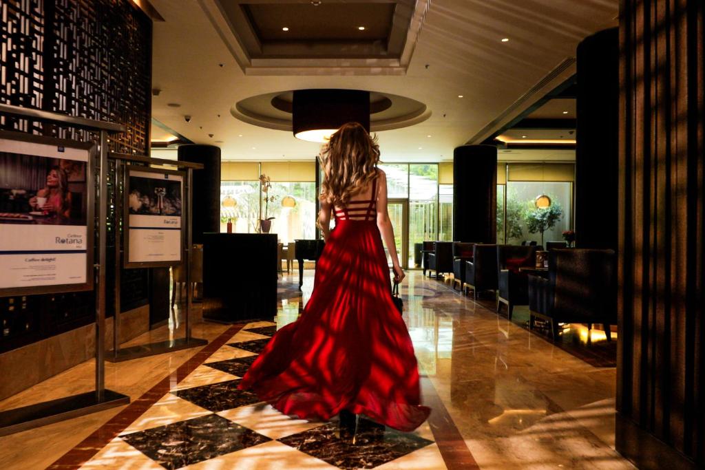 Eine Frau in einem roten Kleid, die den Flur entlang läuft. in der Unterkunft Gefinor Rotana – Beirut in Beirut