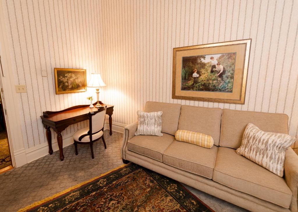 uma sala de estar com um sofá e um piano em Captain Henderson House em Arkadelphia