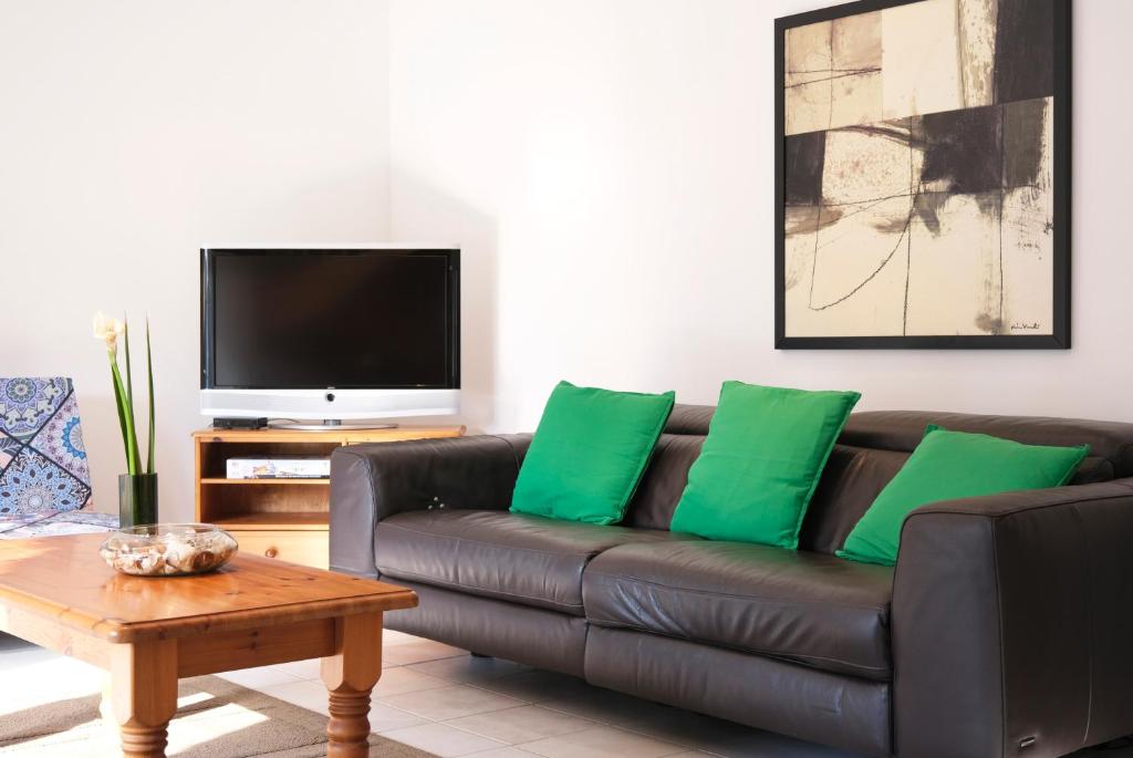 a living room with a brown leather couch with green pillows at Lescoat-le petit paradis in Plestin-les-Grèves