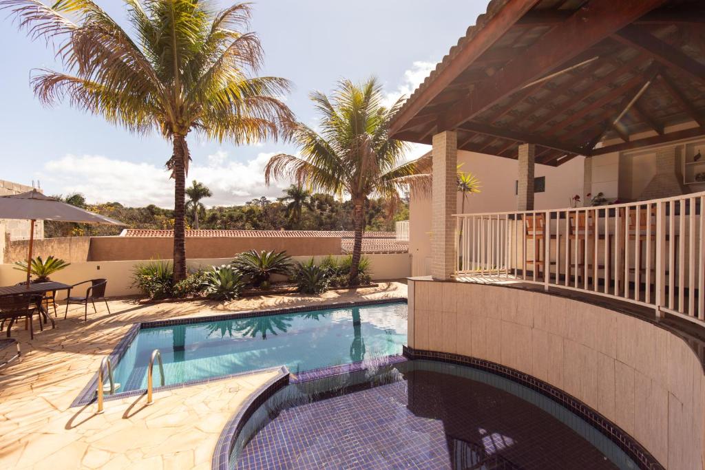 a swimming pool in a house with palm trees at Hospedaria do Lago in Espirito Santo Do Pinhal