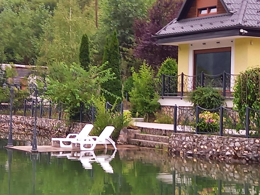 a couple of white chairs sitting in the middle of a pond at Villa Drinski biser sa bazenom in Višegrad