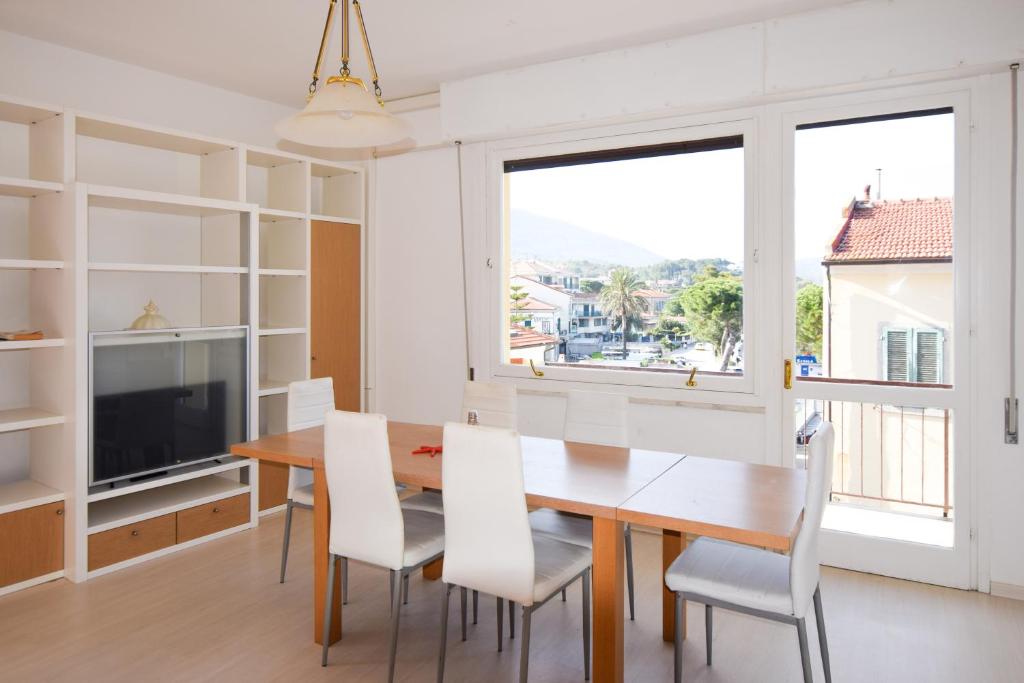 ein Esszimmer mit einem Tisch und Stühlen sowie einem großen Fenster in der Unterkunft Appartamento Sea View Adriana in Marina di Campo