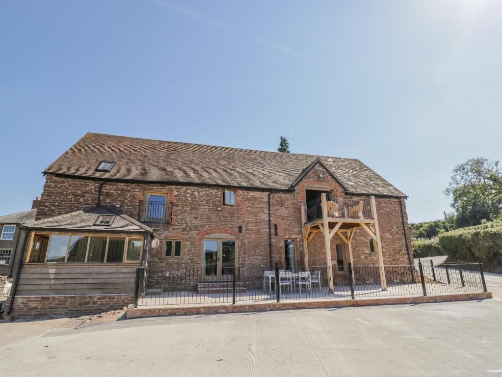 an old brick building with a fence in front of it at Munderfield Mill in Bromyard