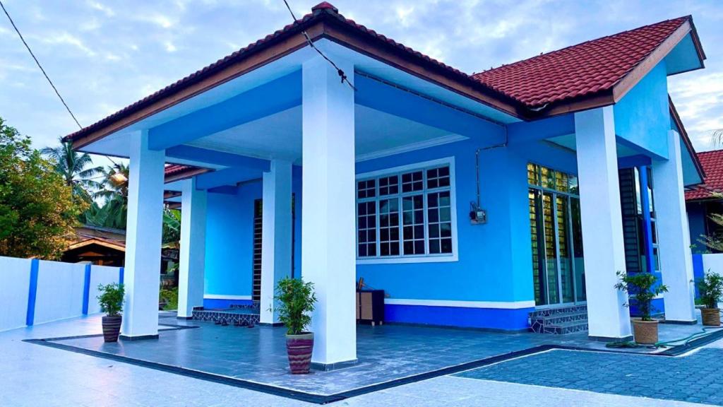 uma casa azul com um telhado vermelho em Seri Idaman Guest House (Pasir Mas) em Kampong Taman