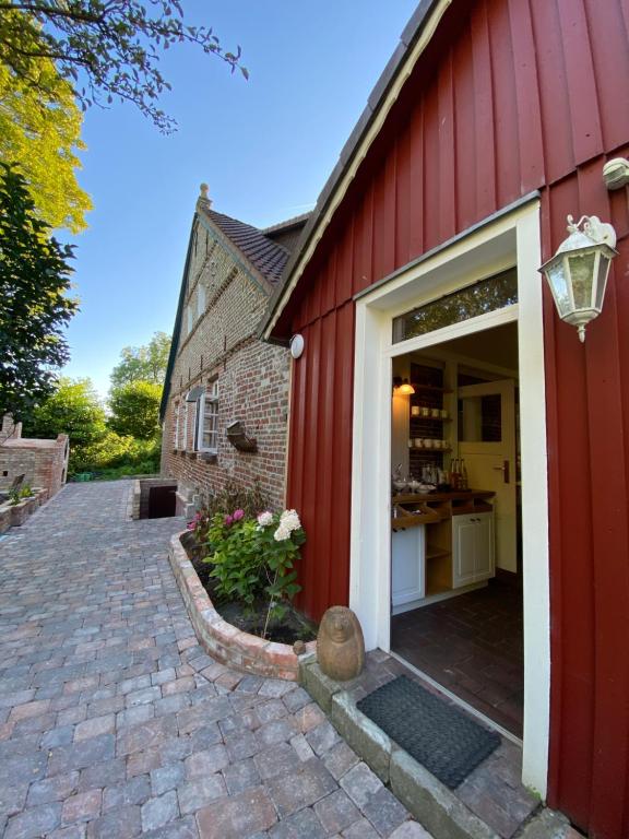 eine rote Scheune mit einer Tür und einer Küche in der Unterkunft Das Anni's in Wangerland
