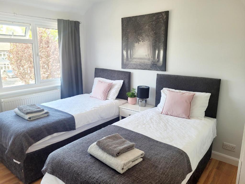 dos camas sentadas una al lado de la otra en un dormitorio en Knollmead House en Surbiton