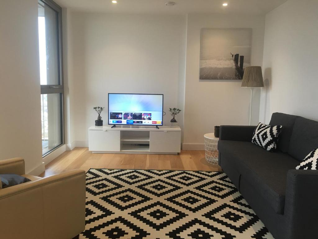 uma sala de estar com um sofá e uma televisão de ecrã plano em LUXURY SERVICED APARTMENT***** em Croydon