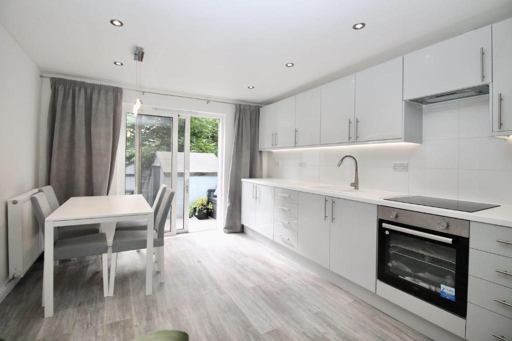 a kitchen with white cabinets and a table and a fireplace at Katie's house in Cumbernauld