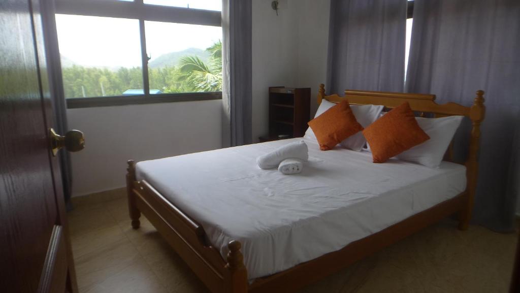 um quarto com uma cama com almofadas laranja e branca em Belle Rose Vue guest house em Baie Sainte Anne