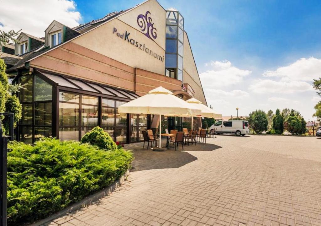 a building with tables and umbrellas in front of it at Hotel Pod Kasztanami in Lublin