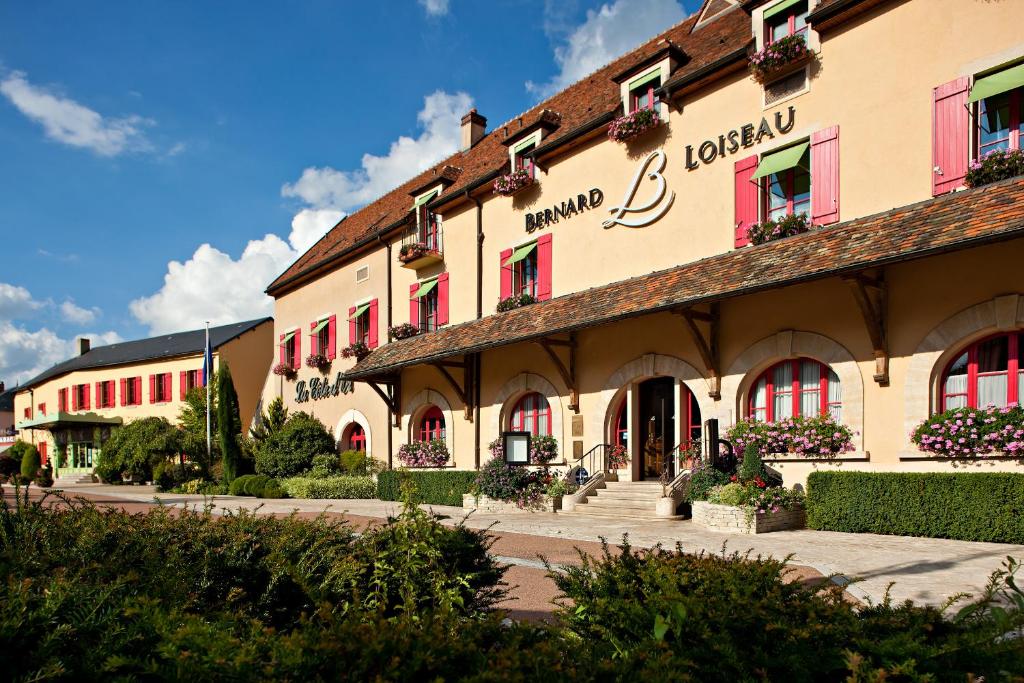 a large building with red windows and plants in front at Relais Bernard Loiseau in Saulieu