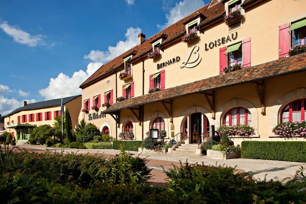 um grande edifício com janelas vermelhas e plantas na frente em Relais Bernard Loiseau em Saulieu