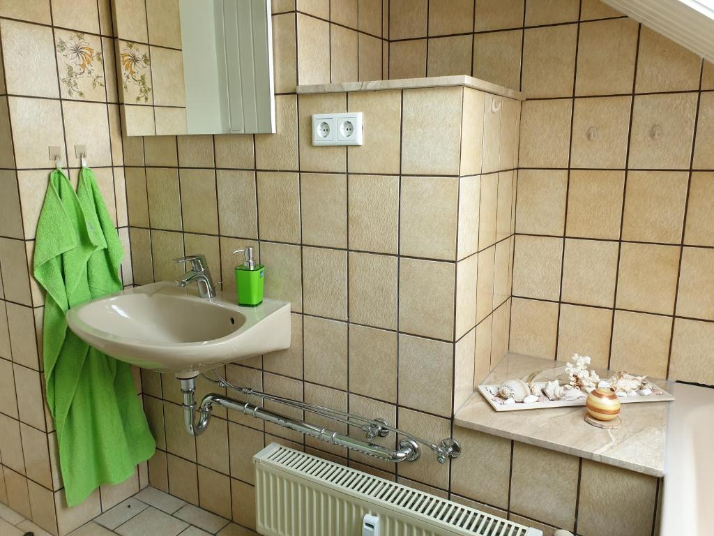a bathroom with a sink and a green towel at Apartment, Boxspringbett, ruhige Lage, Kassel Nähe in Schauenburg