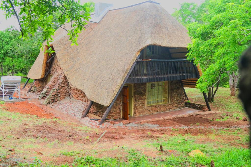a stone house with a thatched roof at Mapelepele Cottage in Simunye