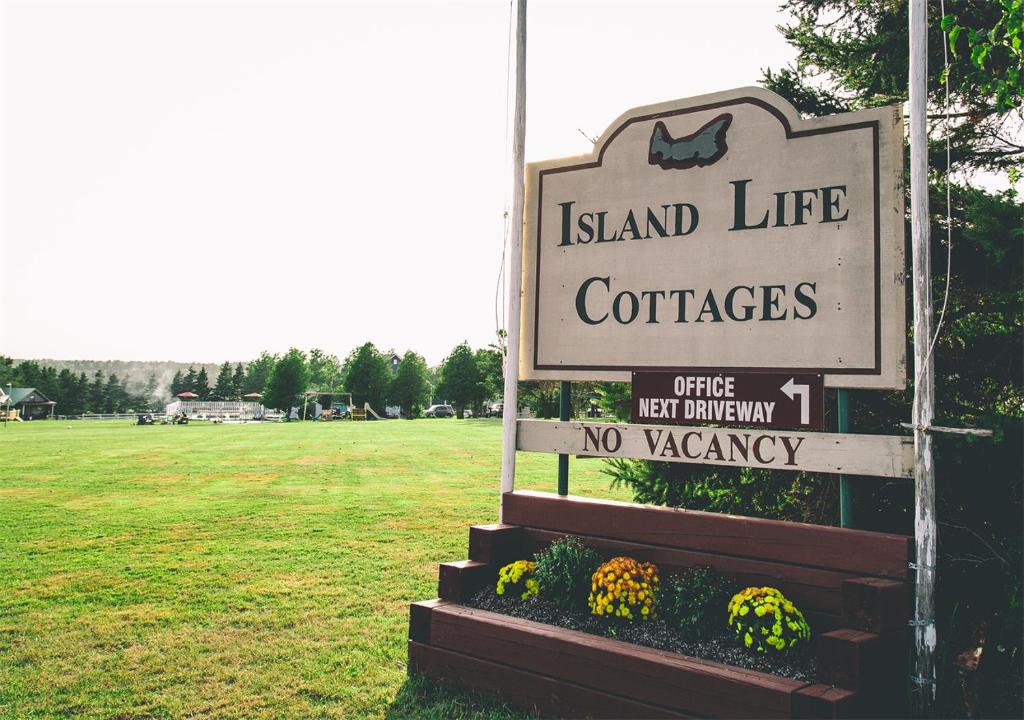 a sign for island life confederacies with a field at Island Life Cottages in Brackley Beach