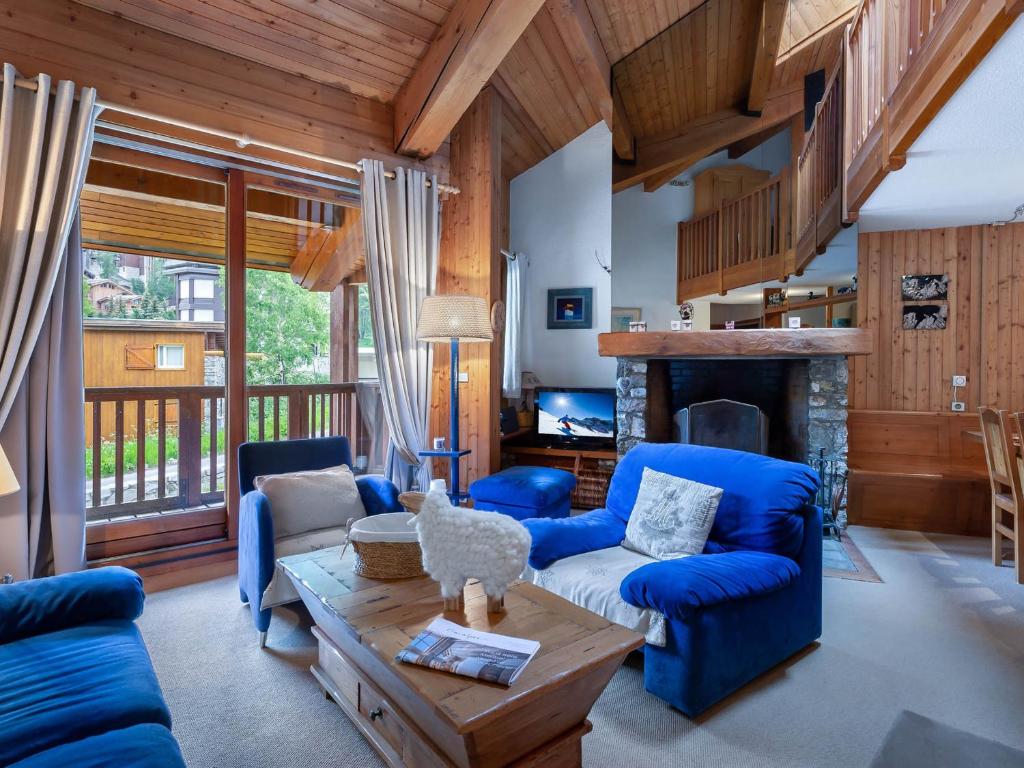 Elle comprend un salon doté d'un mobilier bleu et d'une cheminée. dans l'établissement Duplex 3 Pièces avec Mezzanine, Centre de Val d'Isère, Proche des Pistes, Parking et Cheminée - FR-1-567-24, à Val dʼIsère