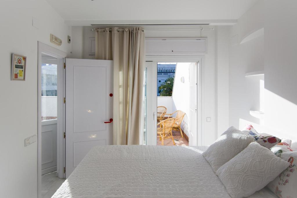 ein weißes Schlafzimmer mit einem Bett und einem Balkon in der Unterkunft Ático con terraza Centro Ciudad in El Puerto de Santa María