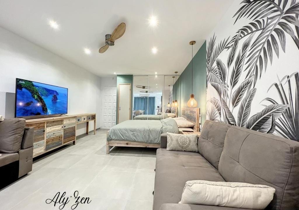 un soggiorno con divano e letto di Studio de charme - Aly'Zen - Magnifique vue mer, les pieds dans l'eau a Le Moule