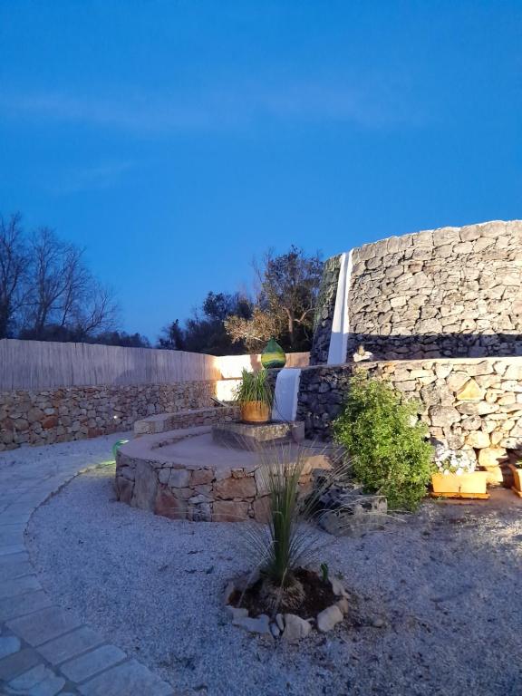 einen Garten mit einer Steinmauer und einer Terrasse in der Unterkunft Trullo "Il fico d'india" in Alliste
