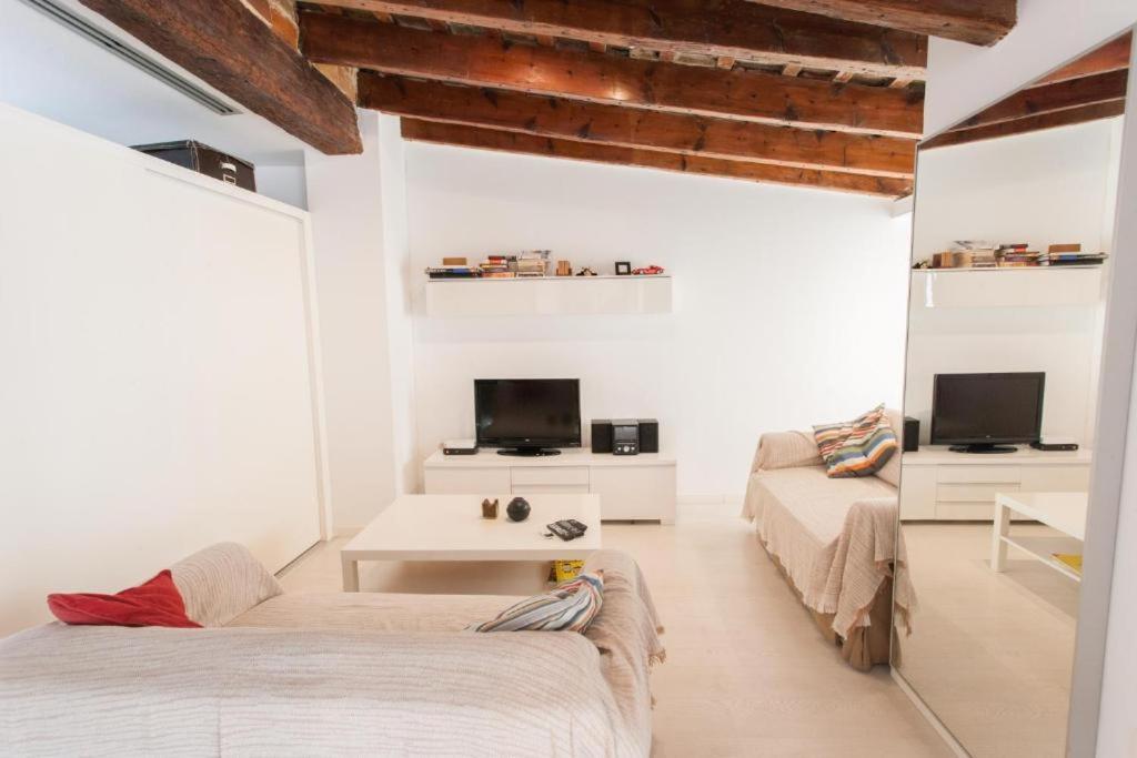 a white room with two beds and a tv at Atico Tapineria in Valencia