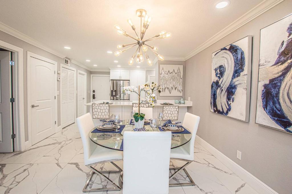a dining room with a glass table and white chairs at Lavish Living ~ Ground Floor Corner Unit in Wesley Chapel