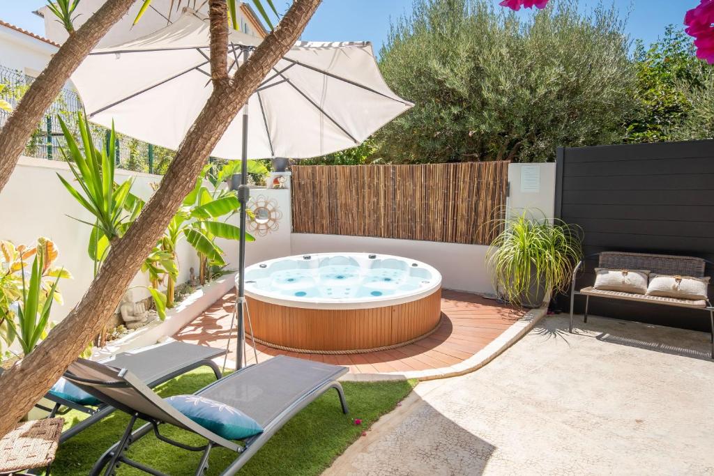 un cortile con vasca idromassaggio, sedie e ombrellone di L'Oursinade - Jolie maison avec Jacuzzi et jardin a Bandol