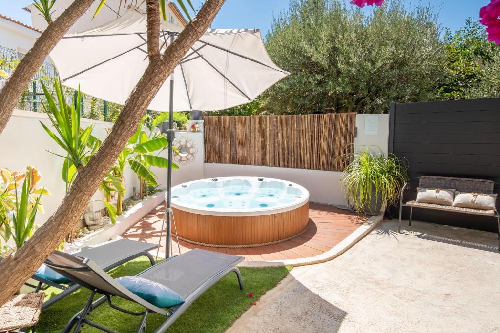 a backyard with a hot tub and chairs and an umbrella at L'Oursinade - Jolie maison avec Jacuzzi et jardin in Bandol