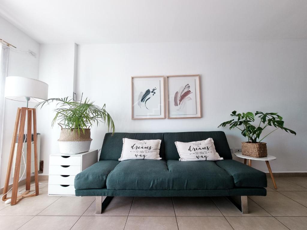 eine grüne Couch in einem Wohnzimmer mit zwei Pflanzen in der Unterkunft Dpto tipo Duplex c pileta Nva Cba in Cordoba
