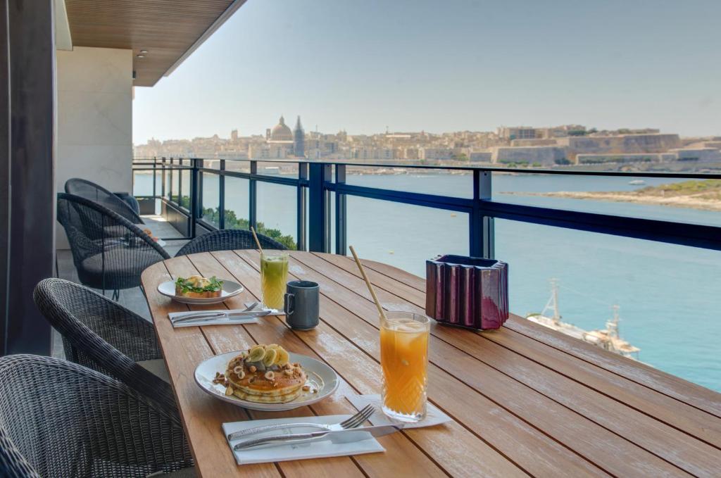 a table with plates of food and drinks on a balcony at Land's End, Boutique Hotel in Sliema