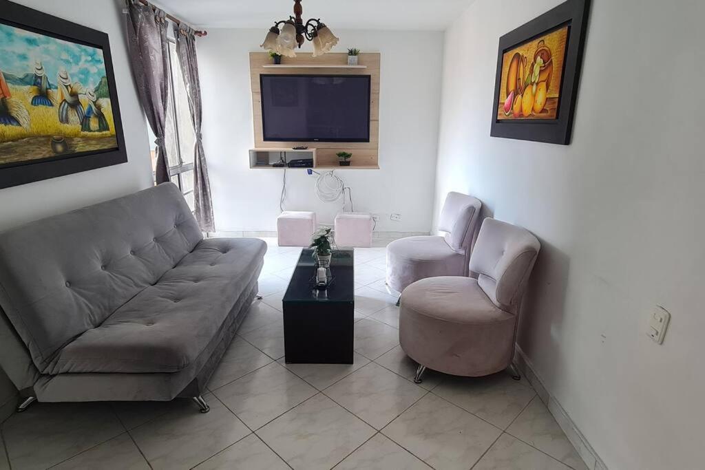 ein Wohnzimmer mit einem Sofa, 2 Stühlen und einem TV in der Unterkunft Hermoso apartamento, con todas las comodidades. in Medellín