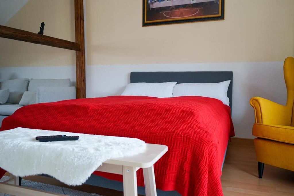 a bedroom with a bed with a red blanket and a table at FULL HOUSE Premium Apartments Jena Holzmarkt in Jena