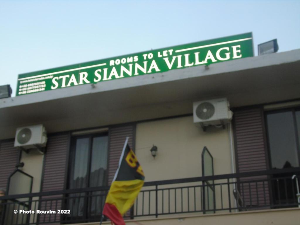 un bâtiment doté d'un drapeau devant lui dans l'établissement Star Sianna Village Rooms to let, à Siána