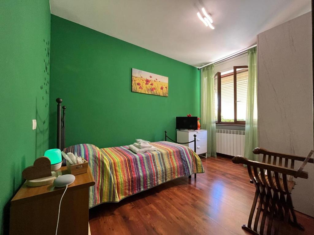1 dormitorio con cama y pared verde en Goccia in Valdorcia Smart Home, en San Quirico dʼOrcia