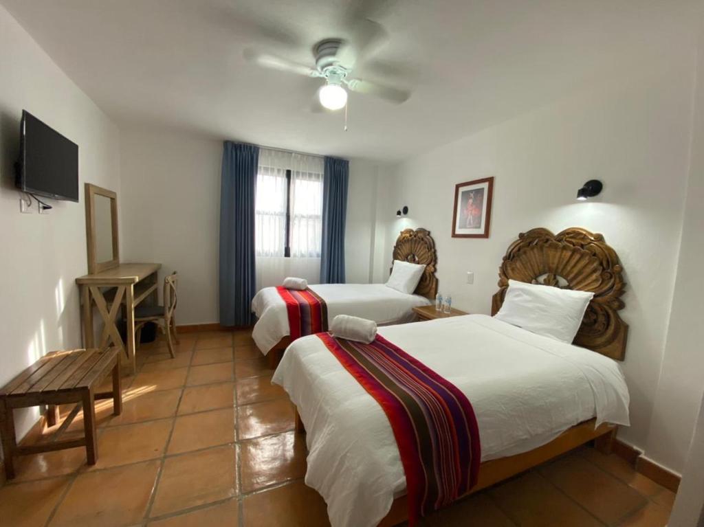 um quarto de hotel com duas camas e uma televisão em Hotel La Lejona em San Miguel de Allende