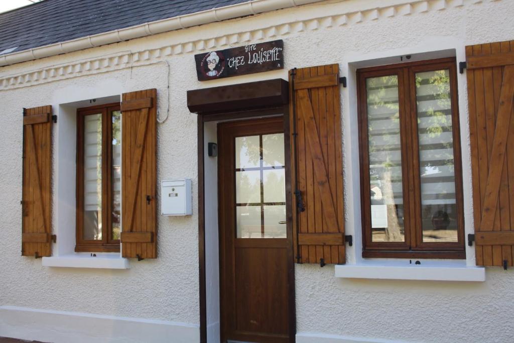 un edificio con persianas de madera y puerta en Gîte chez Louisette en Le Crotoy