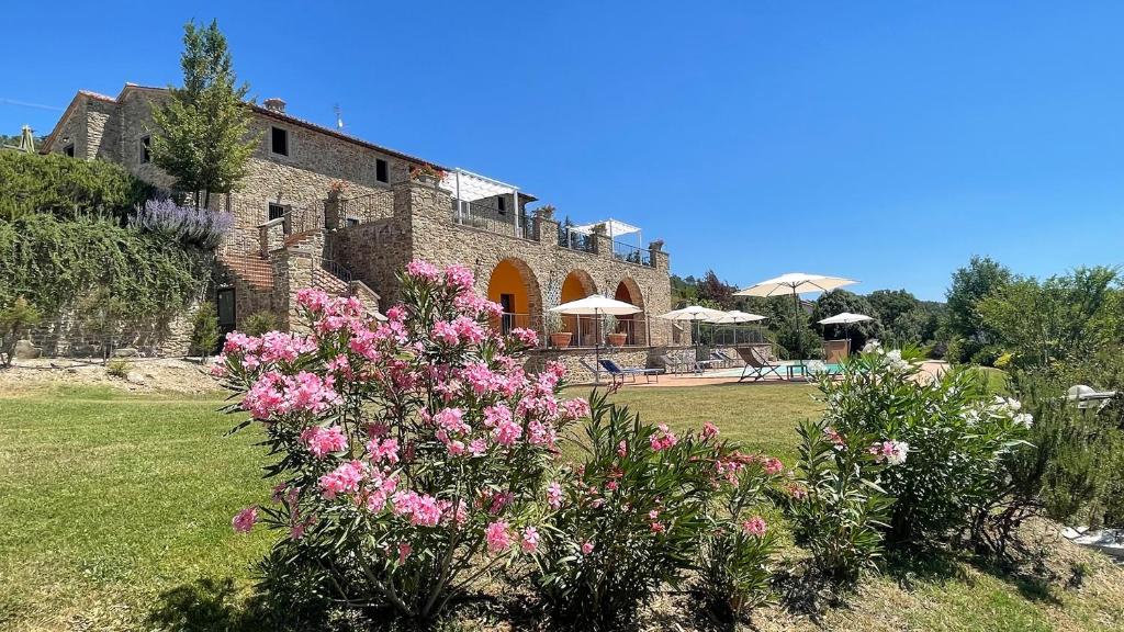 une maison avec des fleurs roses devant une cour dans l'établissement Villa Gosparini, à Lisciano Niccone