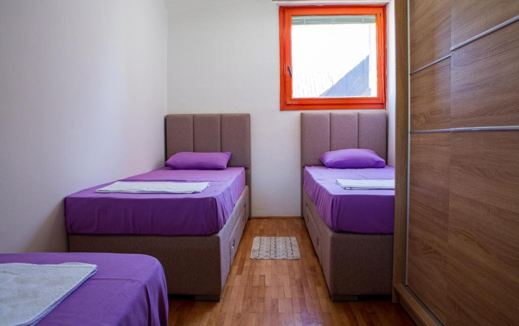 two beds in a room with purple sheets and a window at Urban place apartment Žabljak in Žabljak