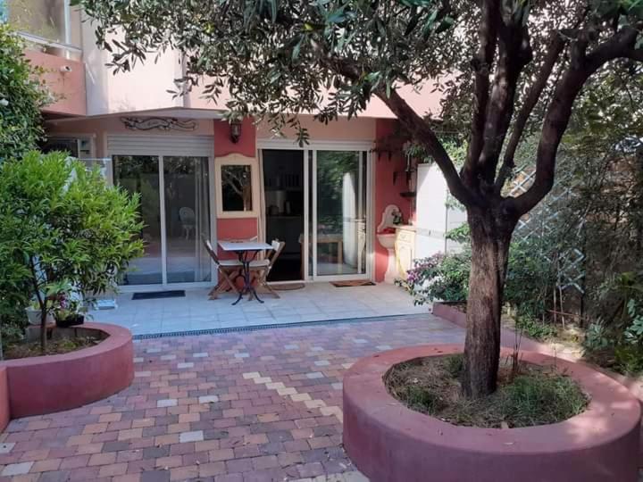 een huis met een boom en een bakstenen patio bij Appartement avec jardin in Roquebrune-Cap-Martin