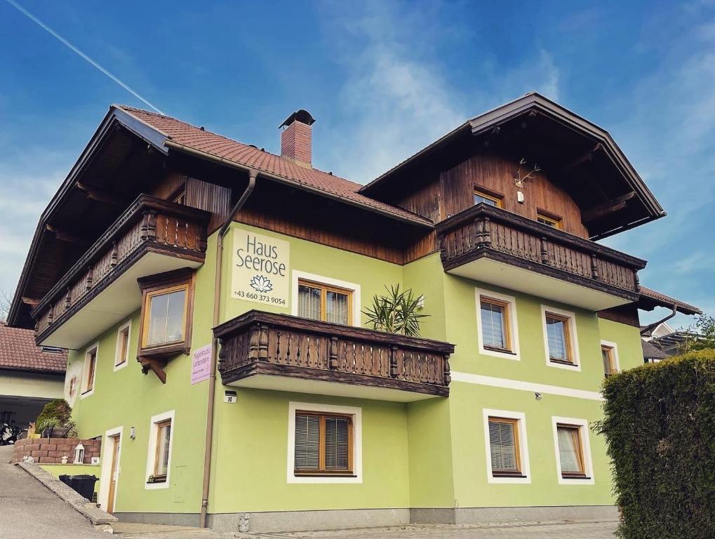 - un bâtiment jaune avec un balcon en bois dans l'établissement Haus Seerose, à Seeboden