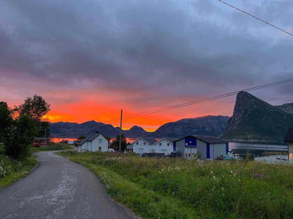 a dirt road next to a village with a sunset at Senja Living in Stonglandseidet