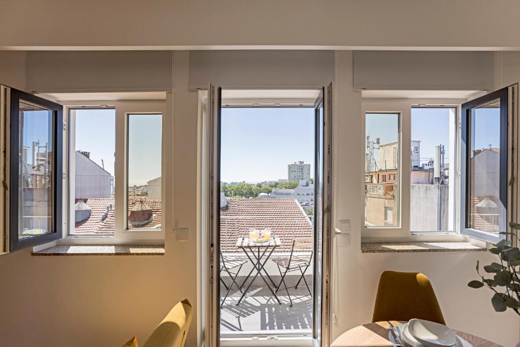 a room with three windows and a view of a city at Urban House by LovelyStay in Porto